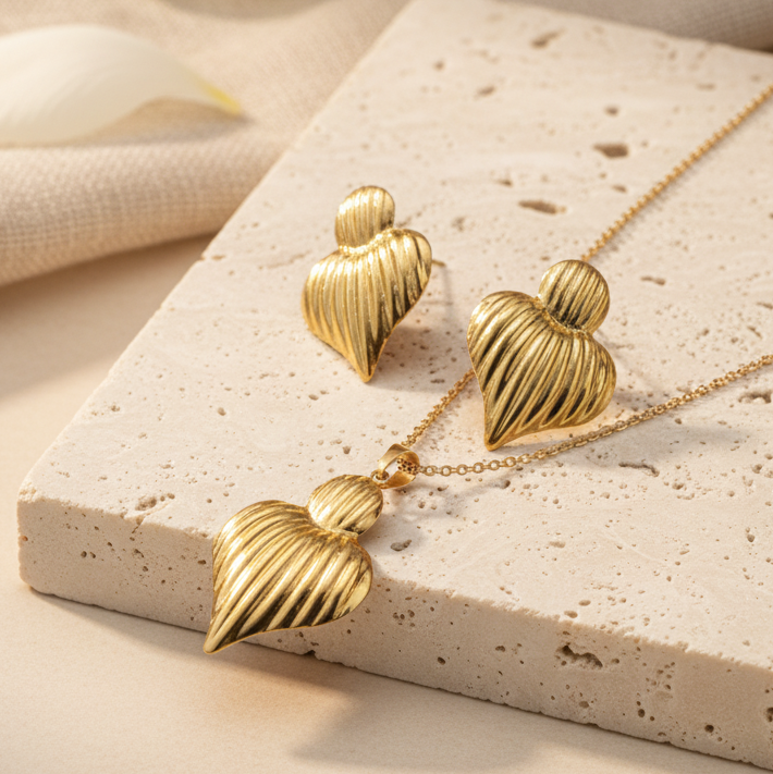 Gold heart-shaped jewelry set on a textured surface with a soft background