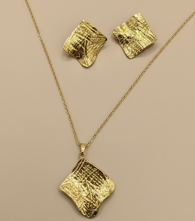 Gold jewelry set with necklace and earrings on a beige background