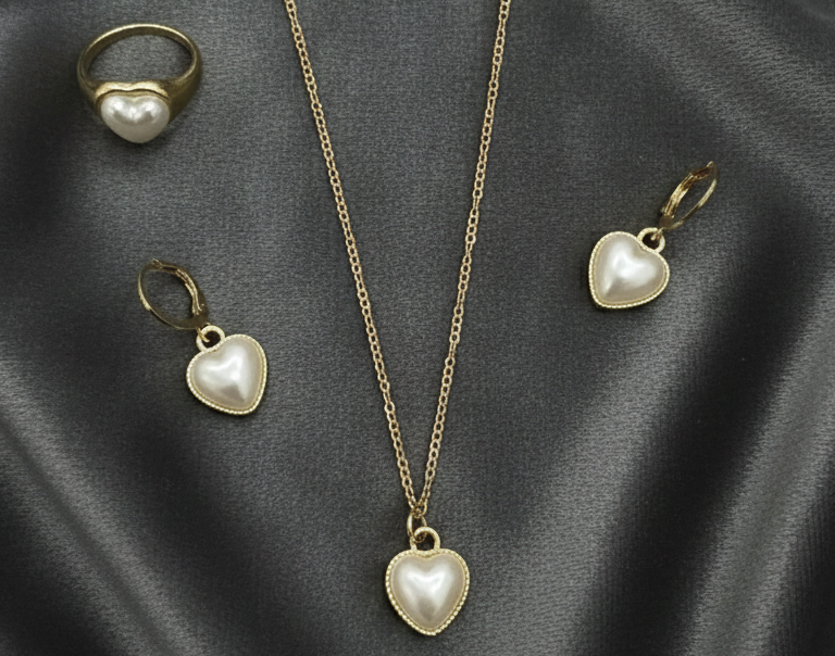 Gold jewelry set with heart-shaped pendants on a dark fabric background
