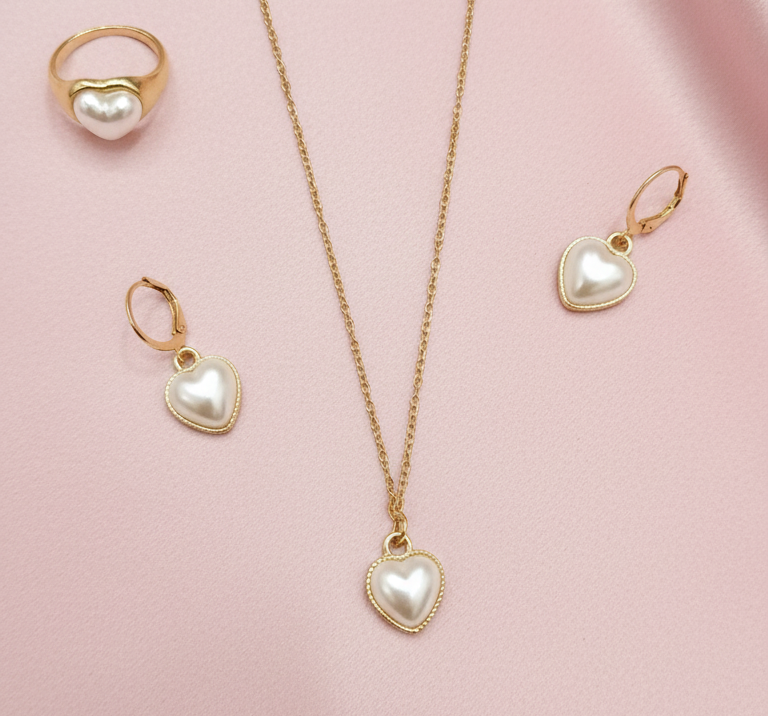 Gold jewelry set with heart-shaped pendants on a pink background