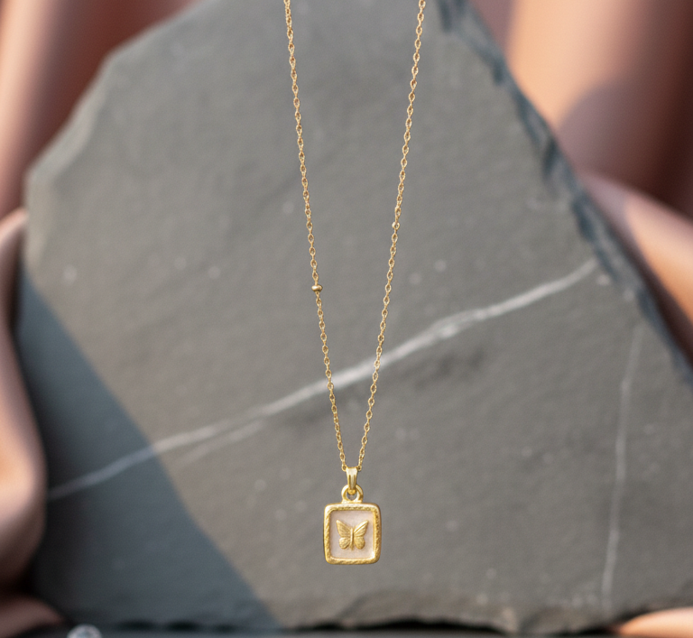 Gold necklace with a small pendant on a gray stone surface