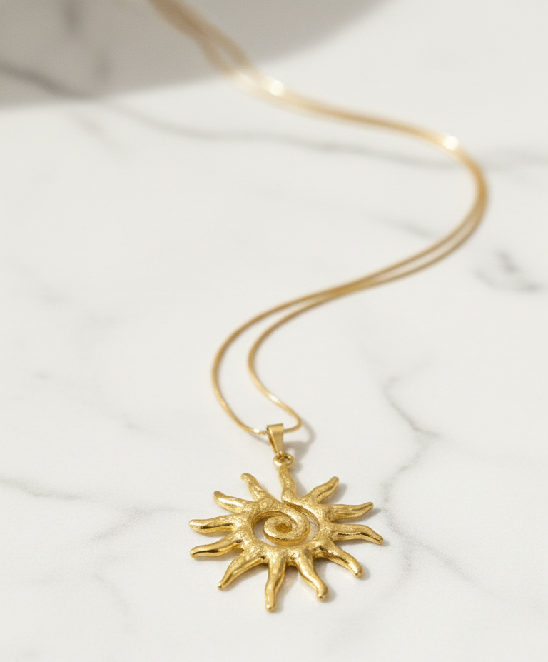 Gold sun-shaped pendant necklace on a white background