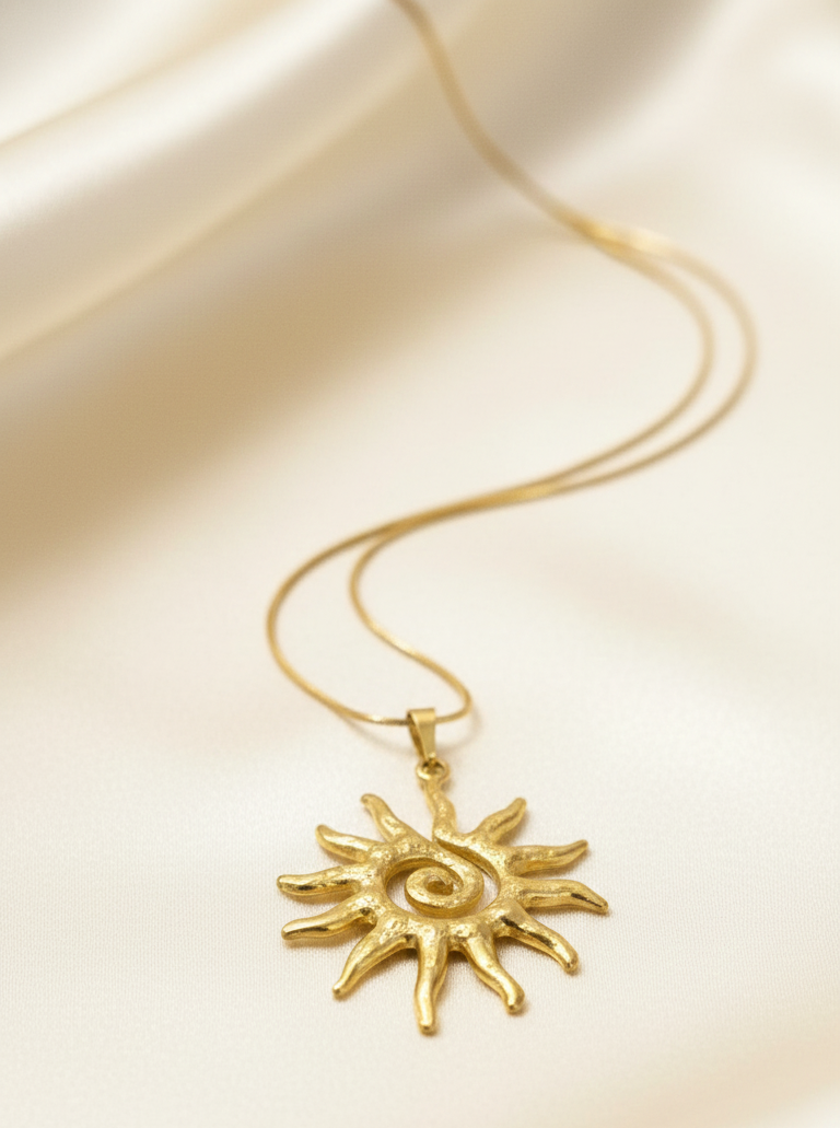 Gold sun-shaped pendant necklace on a beige fabric background