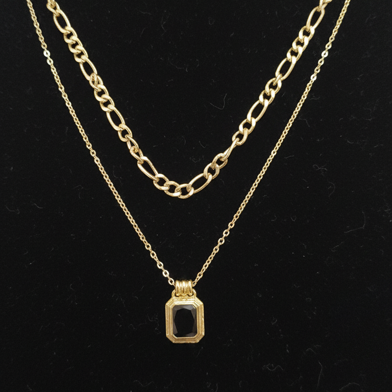 Gold chain necklace with a pendant on a black background