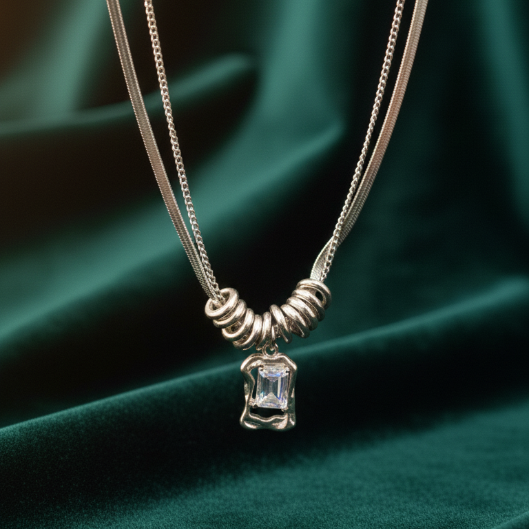 Silver necklace with a pendant on a green fabric background