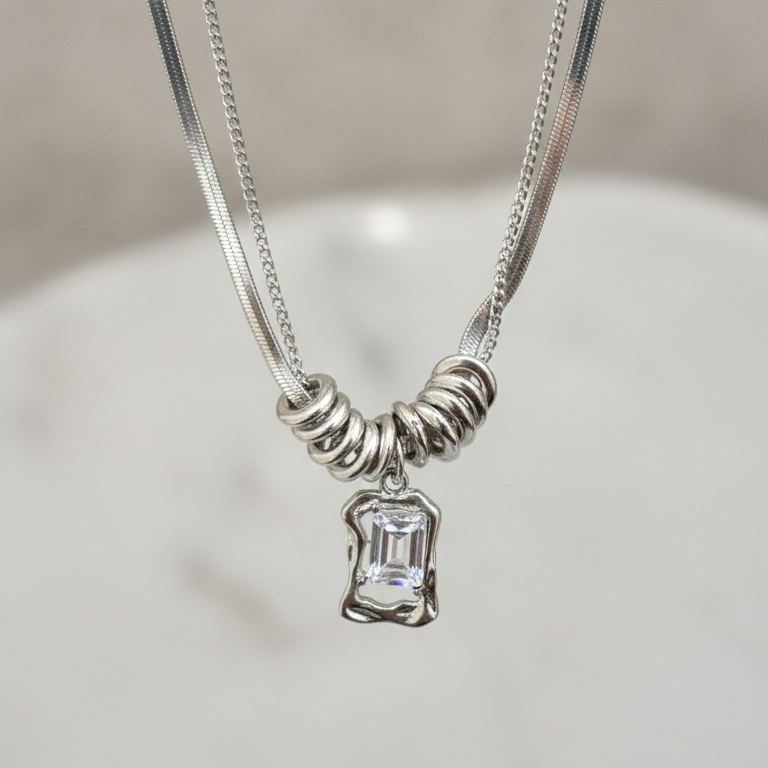 Silver necklace with a pendant on a light gray background