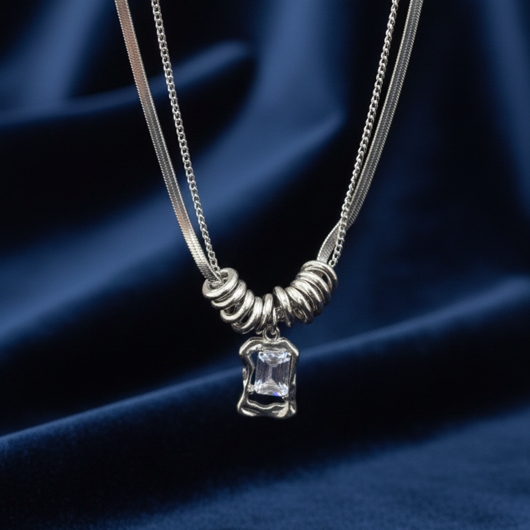 Silver necklace with a clear pendant on a blue fabric background