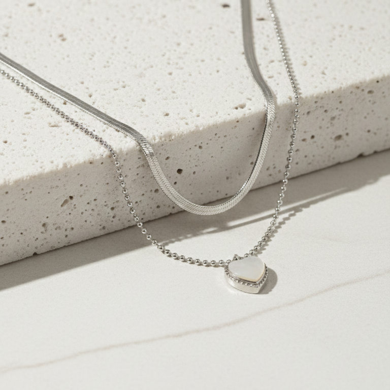 Silver necklace with a small round pendant on a light gray surface