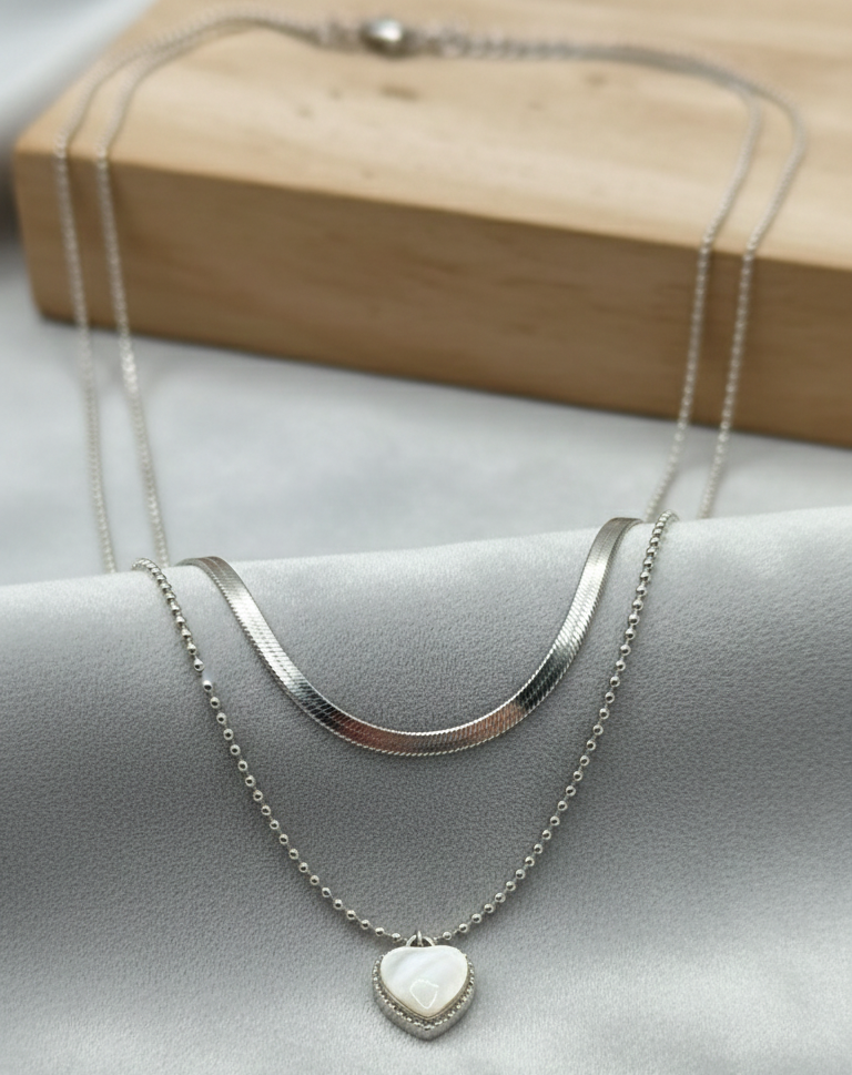 Silver necklace with a heart pendant on a light gray surface