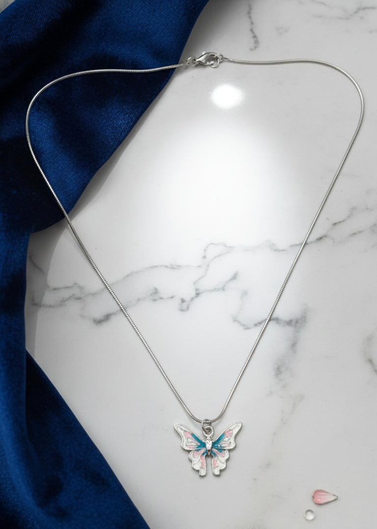 Butterfly pendant necklace on a marble surface with blue fabric background