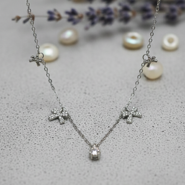 Silver necklace with floral designs on a textured surface with lavender flowers and pearls.