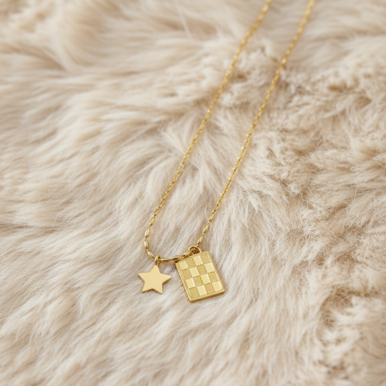 Gold necklace with star and rectangular tag pendant on a fluffy beige surface