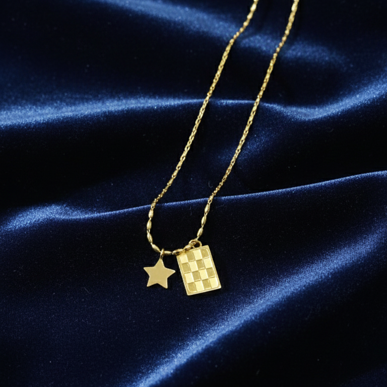 Gold necklace with star and rectangular pendants on a blue satin background